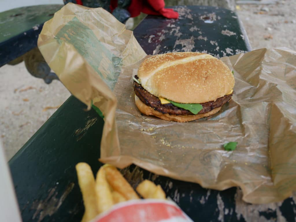 Le burger déballé. On voit les frites en avant plan.