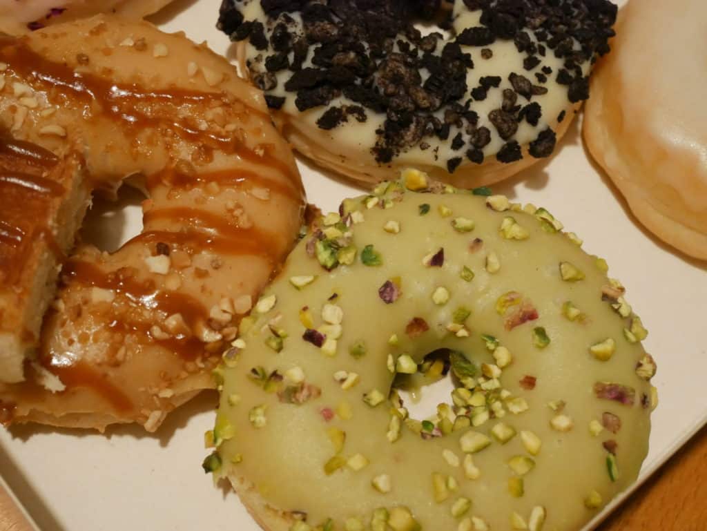 Donuts vus de dessus, on voit que le donut caramel a un morceau de gaufre par dessus, et on voit un donut pistache avec des morceaux de pistache.